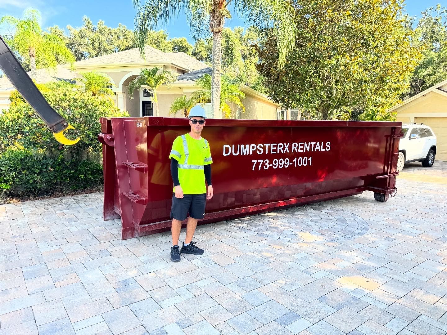 Ali, the owner of DumpsterX Rentals, standing beside a DumpsterX roll-off dumpster