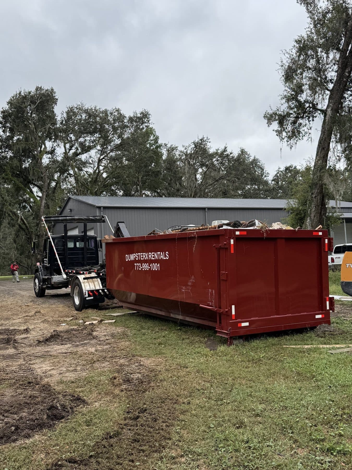 DumpsterX roll-off truck loading a dumpster for pickup